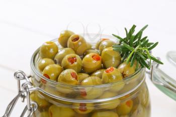 jar of green olives stuffed with red pepper - close up