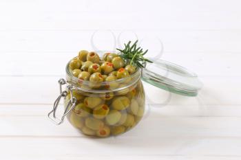 jar of green olives stuffed with red pepper on white background