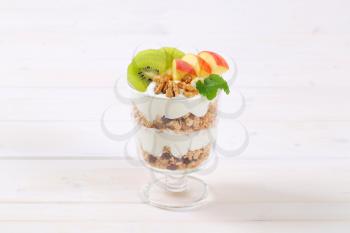 glass of muesli with yogurt and fresh fruit on white background