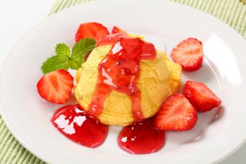 Scoop of yellow ice cream with strawberry sauce