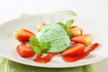 Scoop of green ice cream with fresh strawberries