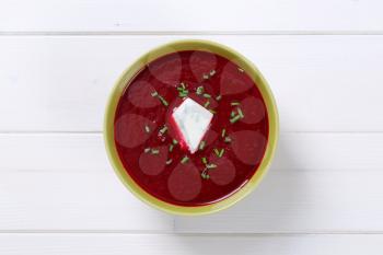 bowl of beetroot cream soup on white wooden background