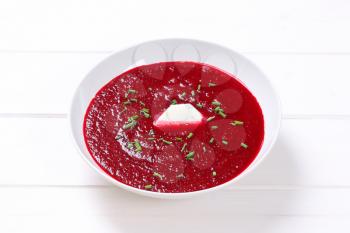 plate of beetroot cream soup on white wooden background