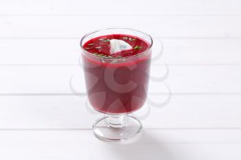 glass of beetroot cream soup on white wooden background