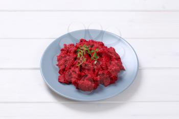 plate of fresh beetroot puree on white wooden background