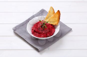 bowl of fresh beetroot puree with toast on grey place mat