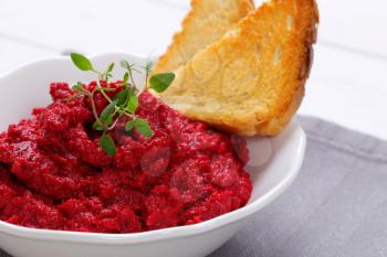 bowl of fresh beetroot puree with toast on grey place mat - close up