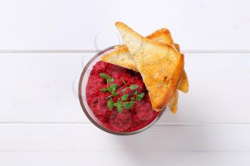 glass of fresh beetroot puree with toast on white wooden background