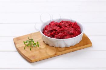 bowl of fresh beetroot puree on wooden cutting board