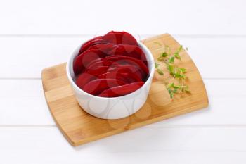 bowl of thin beetroot slices on wooden cutting board