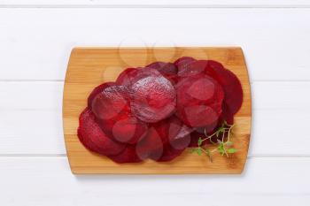 stack of thin beetroot slices on wooden cutting board