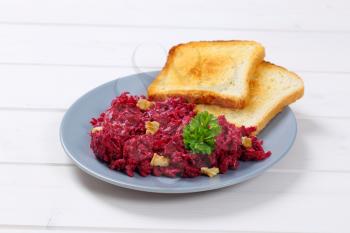 plate of fresh beetroot spread with toast on white wooden background