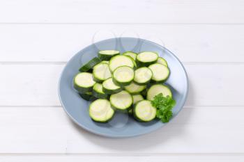 plate of green zucchini slices on white wooden background