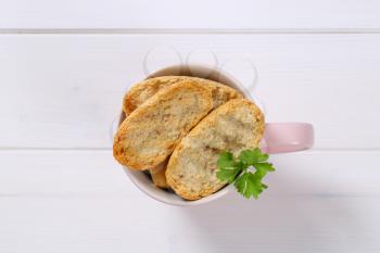 cup of crispy rusks on white wooden background