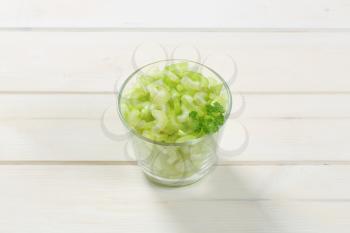glass of chopped celery stems on white wooden background