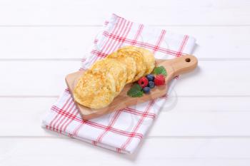 fresh american pancakes with raspberries and blueberries on wooden cutting board