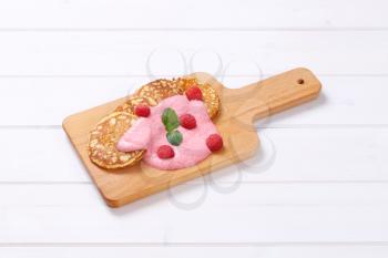 american pancakes with pink yogurt and fresh raspberries on wooden cutting board