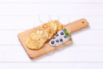 american pancakes with yogurt and blueberries on wooden cutting board