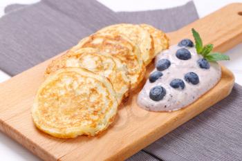 american pancakes with yogurt and blueberries on wooden cutting board - close up