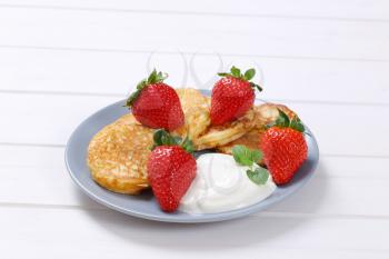 plate of american pancakes with white yogurt and fresh strawberries on white wooden background