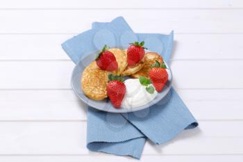 plate of american pancakes with white yogurt and fresh strawberries on blue place mat