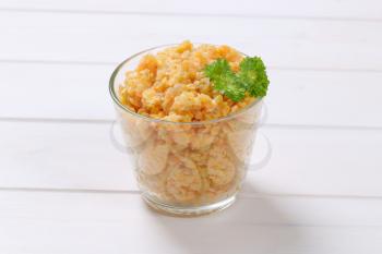 Cooked red lentils in glass on white wooden background
