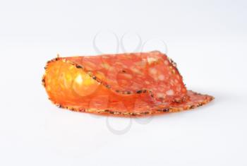 Thin slice of black pepper-coated salami speckled with pieces of Comte cheese