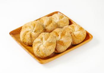 six whole wheat bulkie rolls on square wooden plate