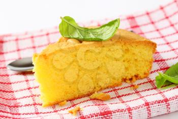 Slice of lemon sponge cake on checked tea towel
