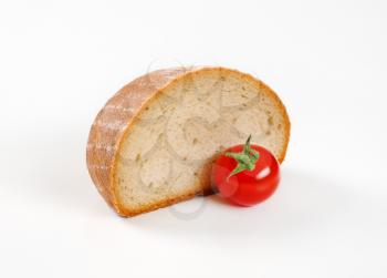 Half a loaf of continental bread and tomato on white background