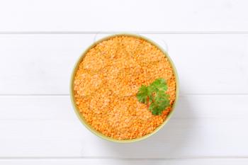 bowl of peeled red lentils on white wooden background