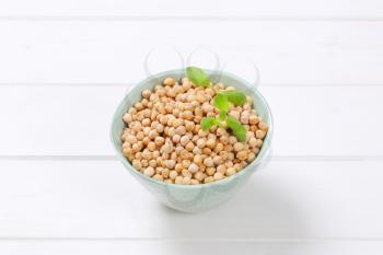 bowl of raw chickpeas on white wooden background