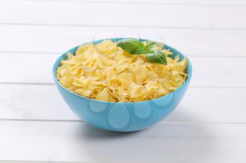 bowl of quadretti - square shaped pasta on white wooden background