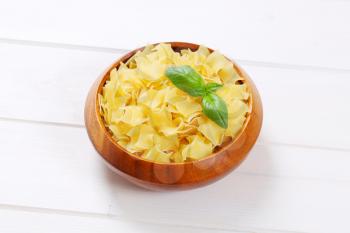 bowl of quadretti - square shaped pasta on white wooden background