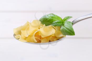 spoon of quadretti - square shaped pasta on white wooden background