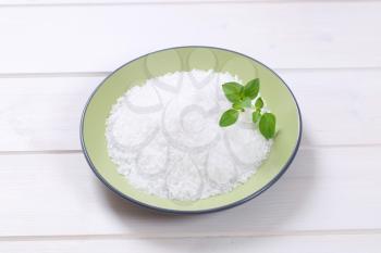 plate of coarse grained sea salt on white wooden background