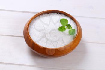 bowl of coarse grained sea salt on white wooden background
