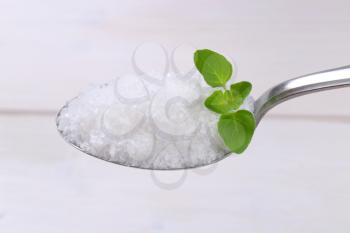 spoon of coarse grained sea salt on white wooden background