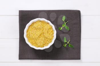 bowl of dry wheat bulgur on dark grey place mat
