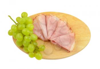 ham slices with bunch of white grapes on oval wooden cutting board