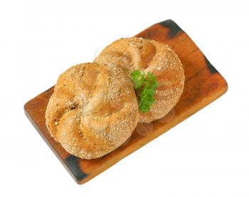 two whole wheat buns on wooden cutting board