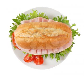 crusty roll sandwich with ham on white plate