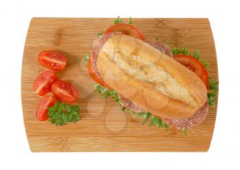 crusty roll sandwich with salami on wooden cutting board
