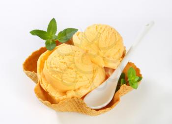 Scoops of orange ice cream in a waffle basket