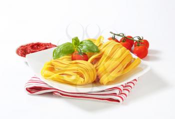 Bundles of thin ribbon pasta and tomato paste