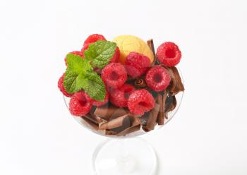 Scoops of ice cream topped with chocolate curls and raspberries