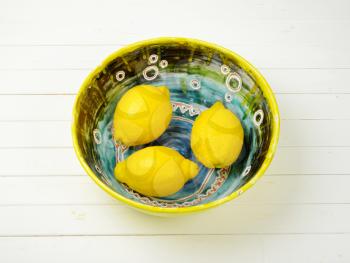 bowl of fresh juicy lemons on white wooden background
