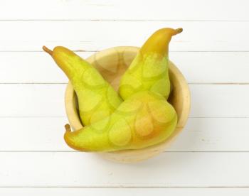 three yellow pears in wooden bowl