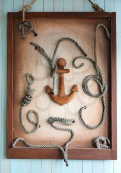 Framed wooden anchor and knots as decoration on wall
