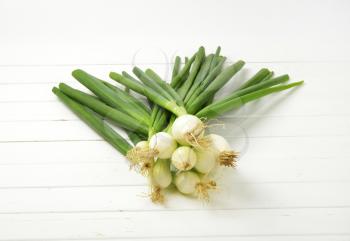 bunch of spring onion on white wooden background